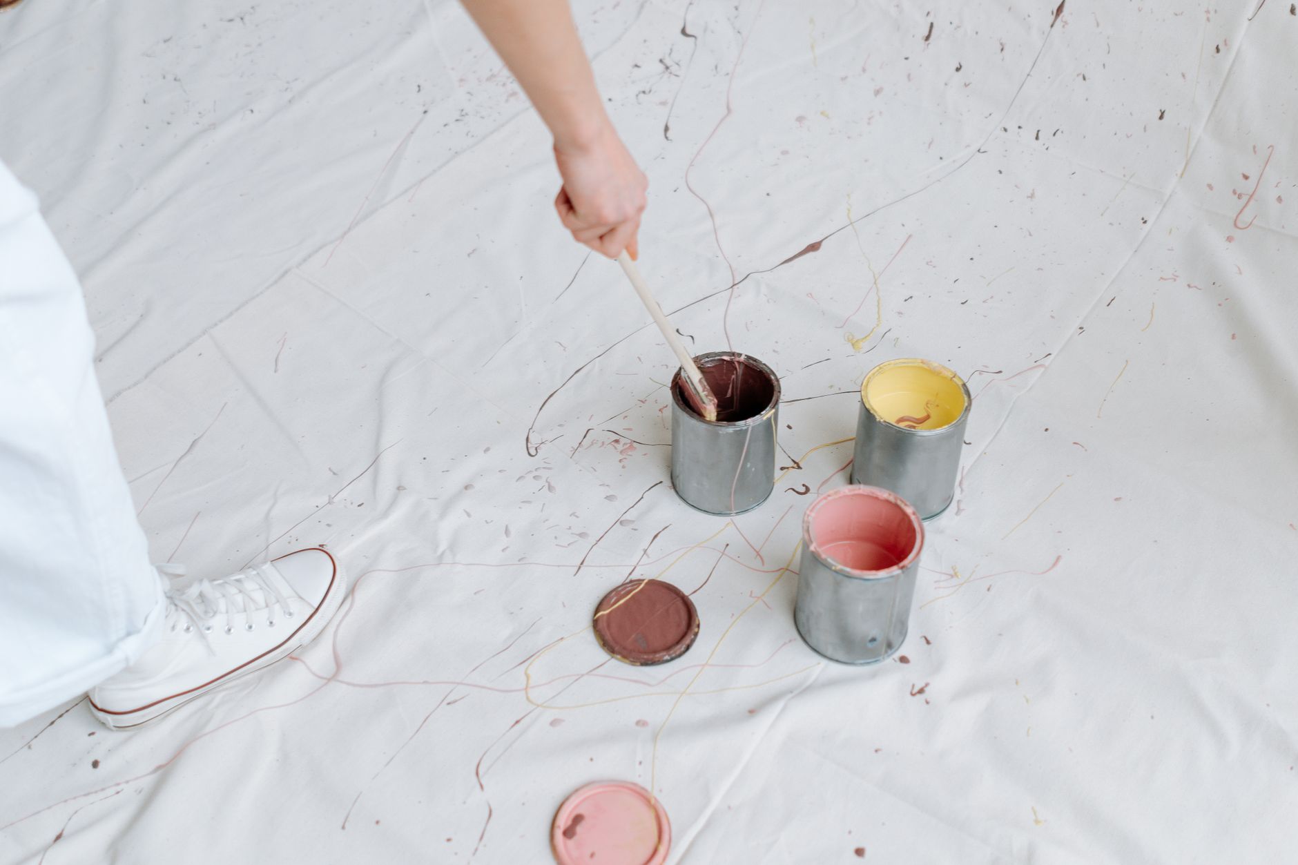 Close-up of paint cans and brushes on a white fabric backdrop, creating a messy artistic scene in Torrance, CA